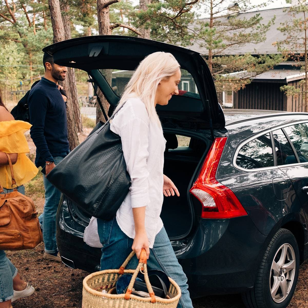 En kvinna och en man packar in saker i bilens baklucka.