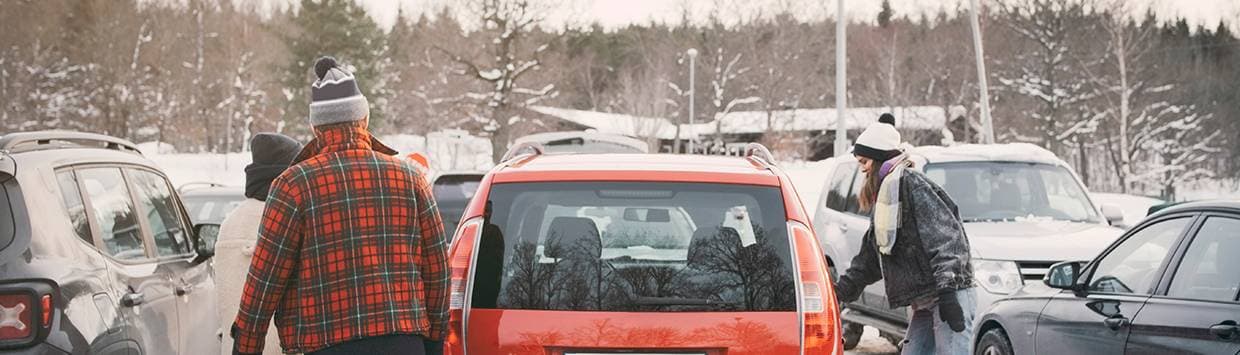 Människor som kommer fram till en bil på parkeringen