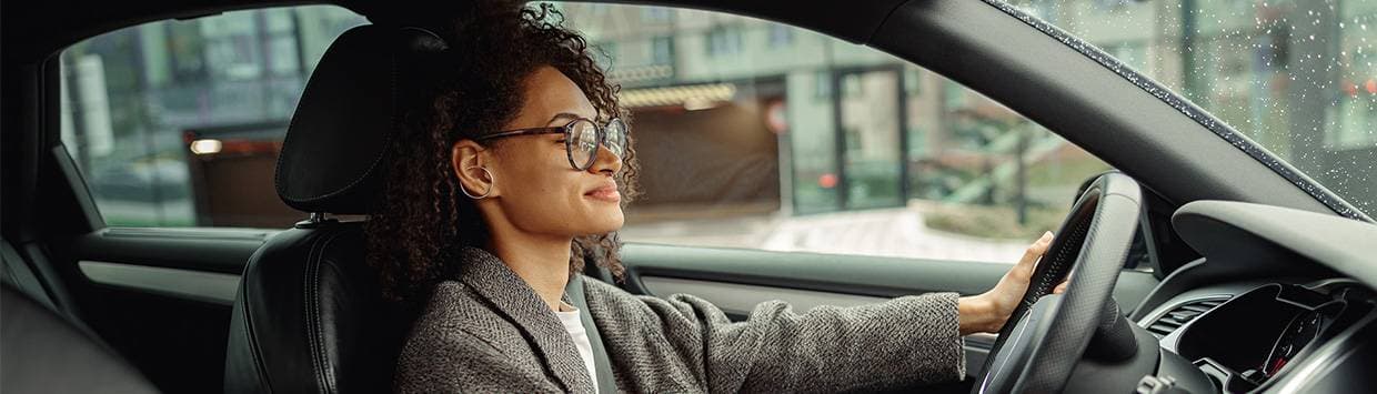 En kvinna som sitter vid ratten i en bil.