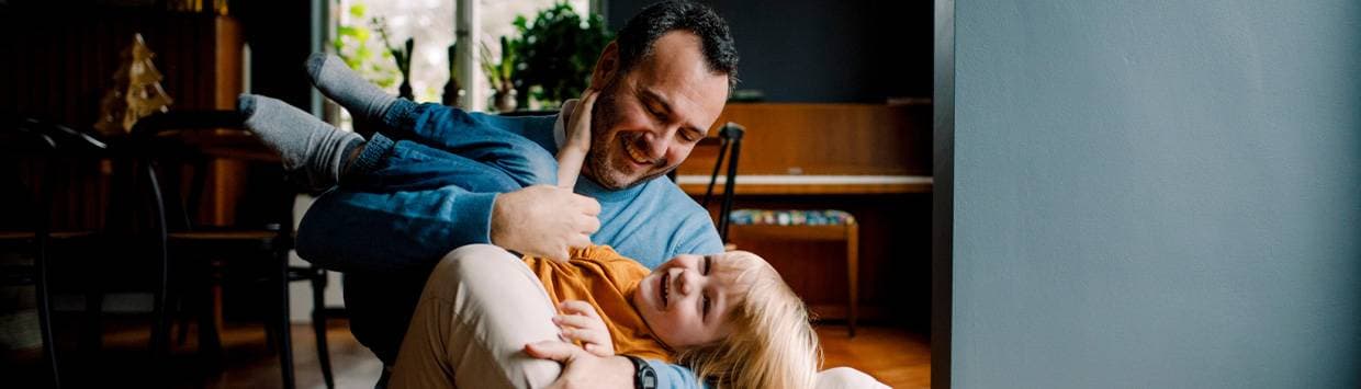 Man som sitter på golvet och leker med ett barn