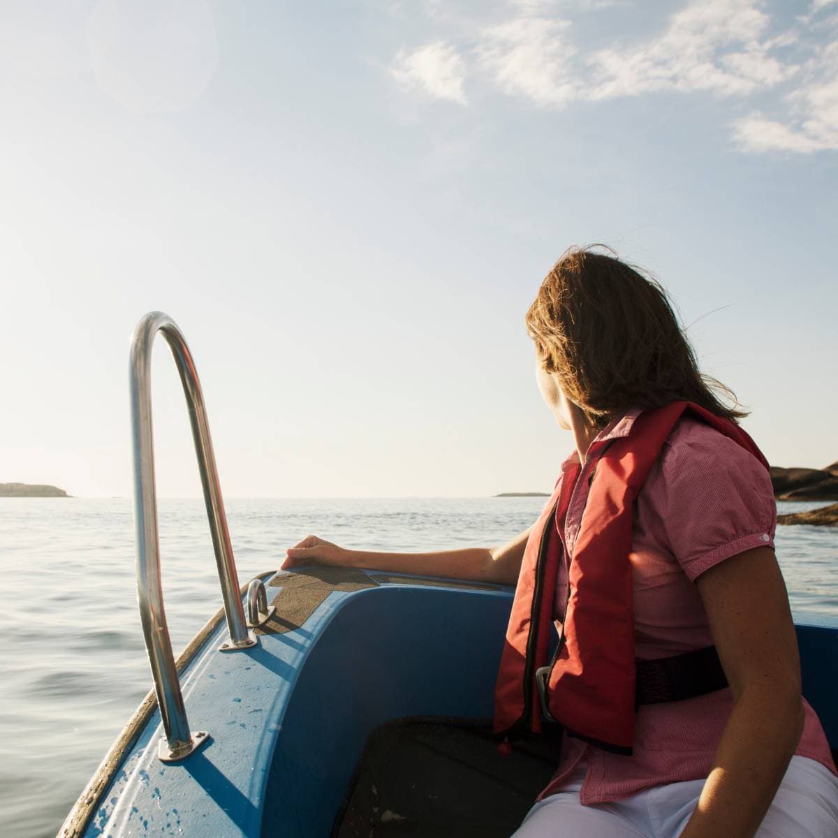 En kvinna sitter i fören på en båt och blickar ut över vattnet.