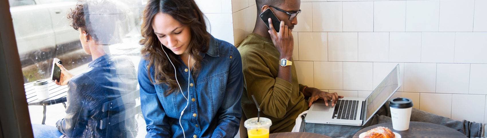 Kvinna och man sitter på ett café och arbetar på varsin dator