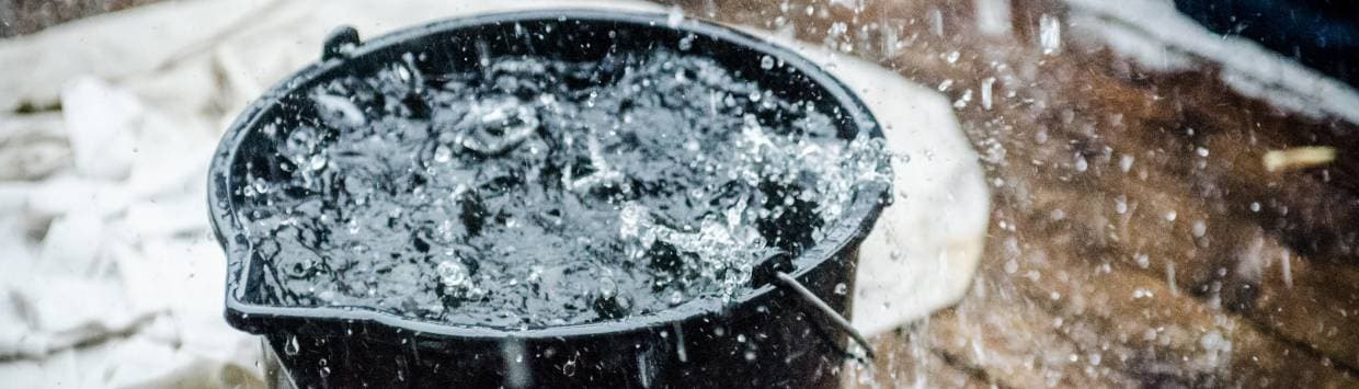 Överfylld hink med vatten som fylls av regndroppar