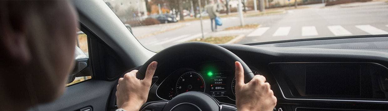 Man i bil som närmar sig ett övergångsställe med en gångtrafikant