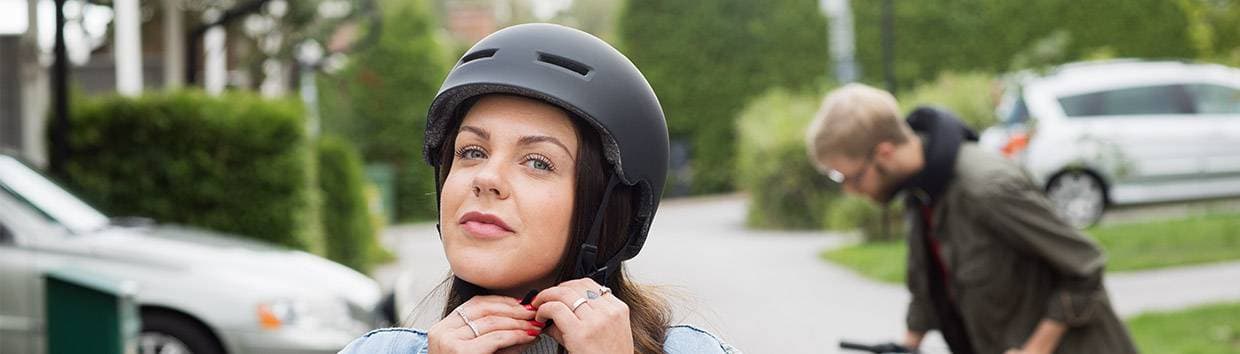 Kvinna som spänner fast cykelhjälm