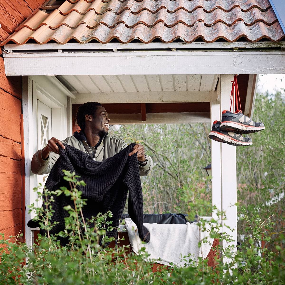 En man skakar en tröja på farstukvisten till ett fritidshus.