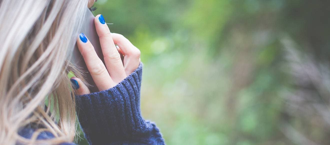 En kvinna sett bakifrån håller sin telefon mot örat