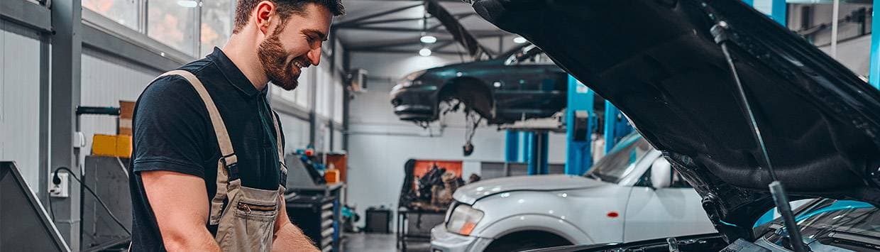 Bilmekaniker som tittar ner under en motorhuv