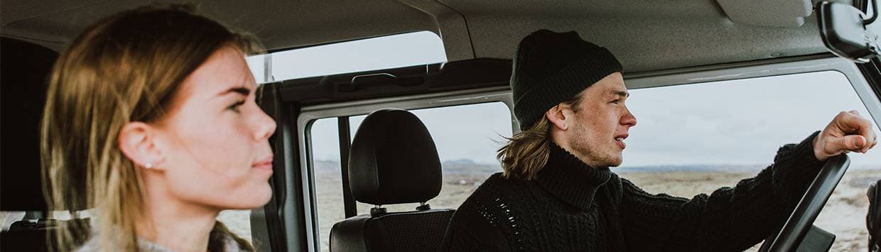 En kille kör en bil och har en tjej bredvid sig som passagerare