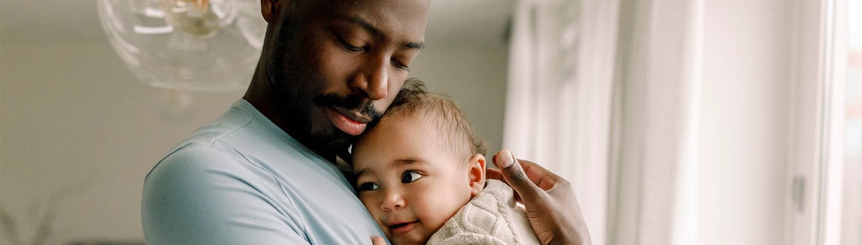 Man som håller en bebis intill sig
