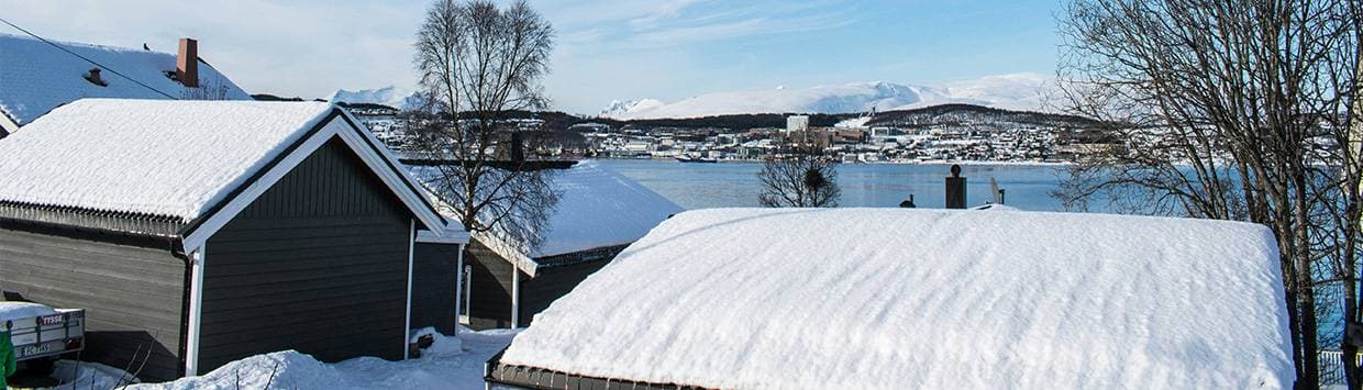 Hustak som är täckta av snö med en sjö i bakgrunden