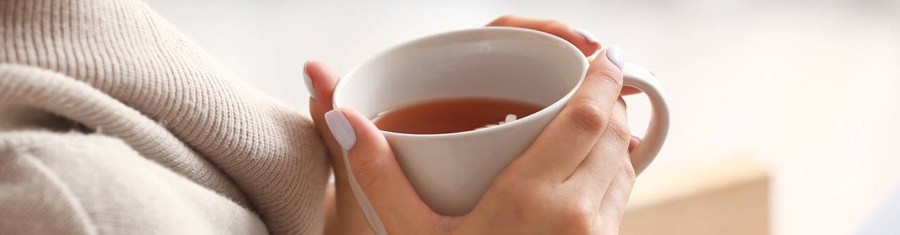 händer som håller i en kopp med te