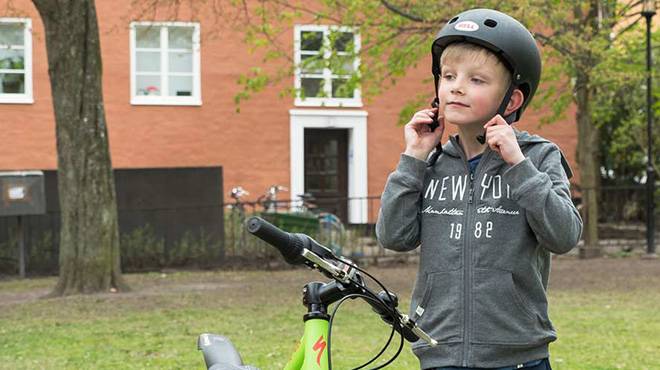 barn som tar på sig cykelhjälm