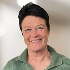 Leende skaderegleraren Marie-Louise, med kort hår och grön mysig tröja.