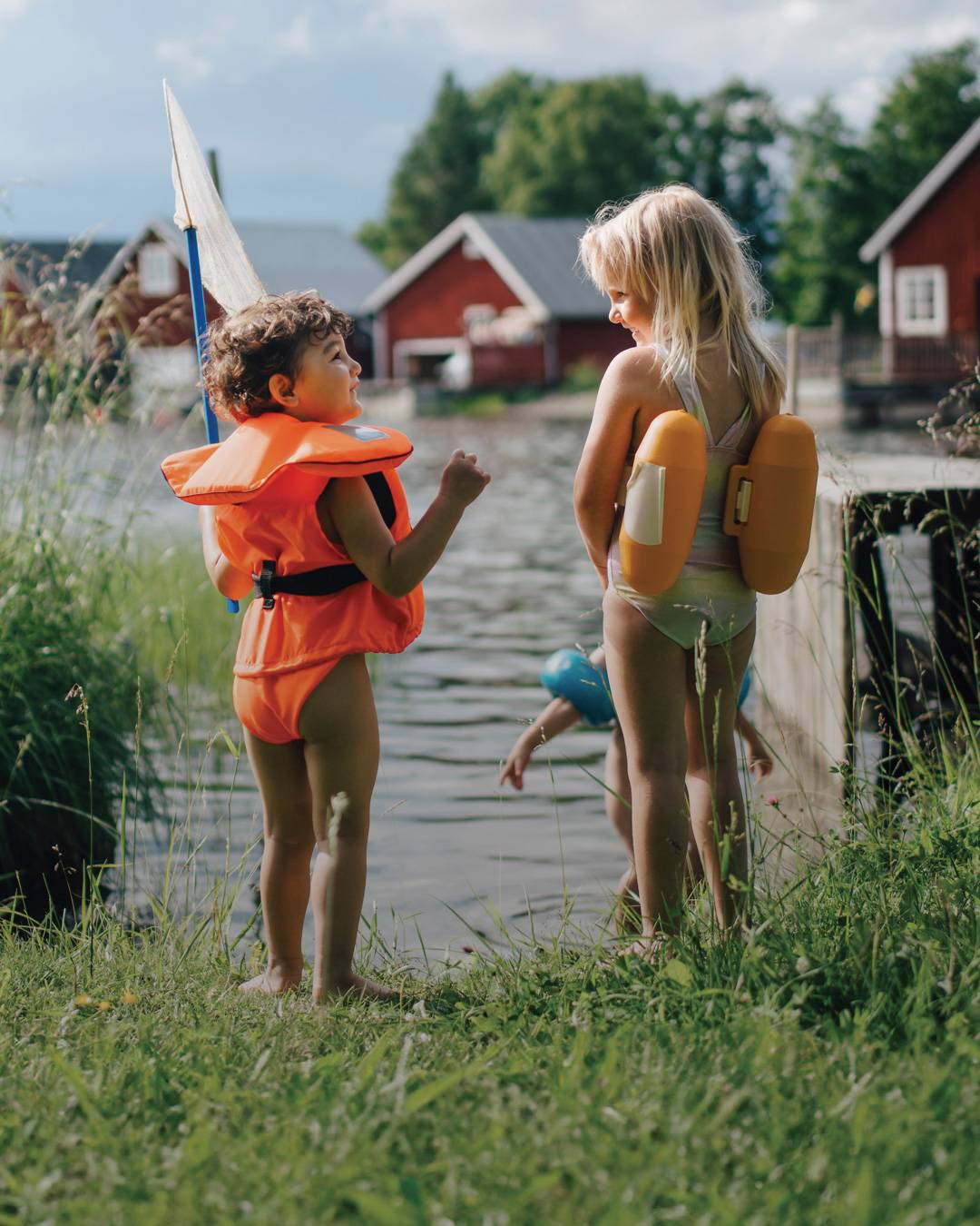 Två barn står och pratar vid vattnet.