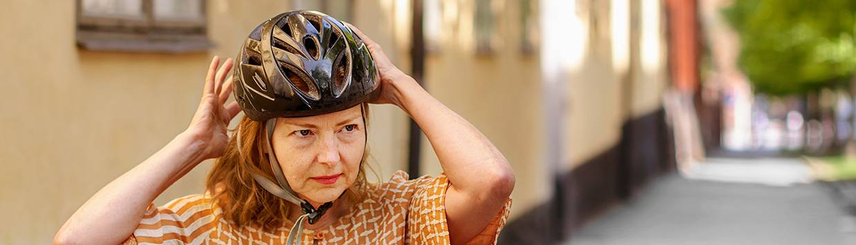 kvinna som tar på sig cykelhjälm